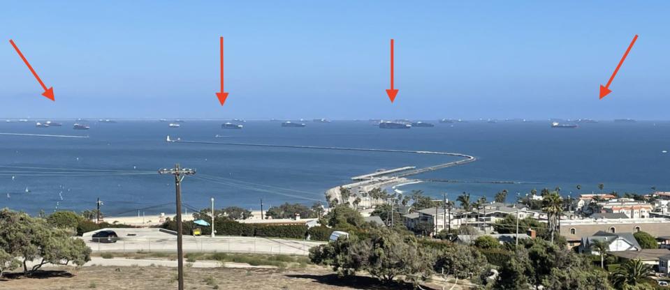 Red arrows point to the dozens of cargo ships waiting outside the port of Los Angeles.