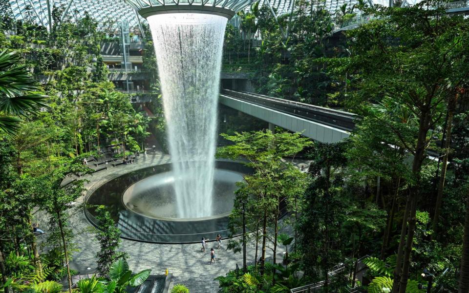 People walk around the rain vortex at Jewel Changi Airport in Singapore on June 23, 2021.  - AFP