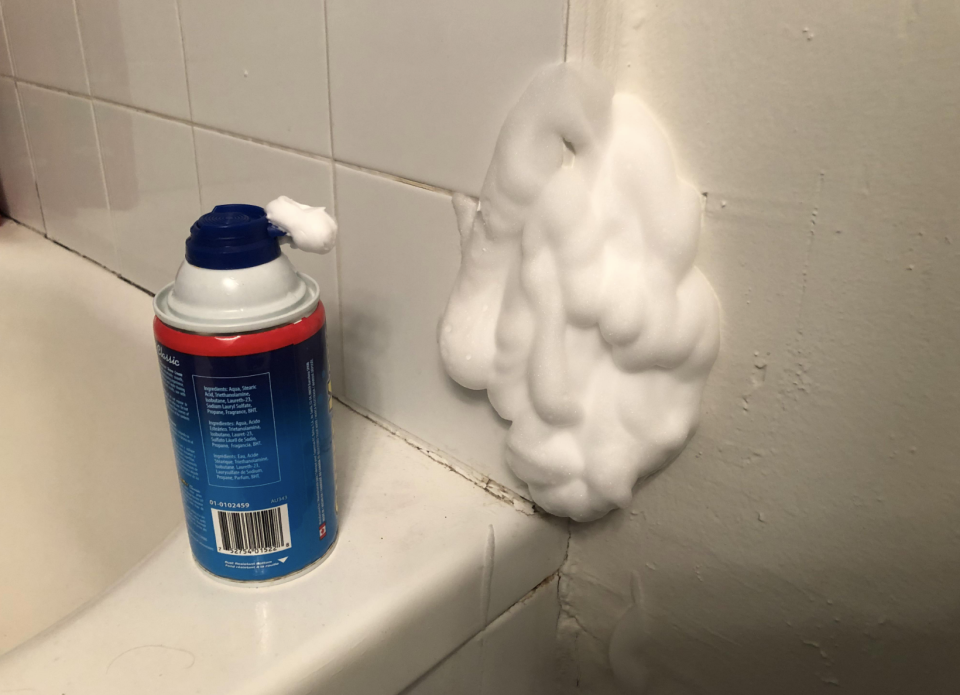 A large pile of shaving cream has been sprayed on the wall so you can't see the spider