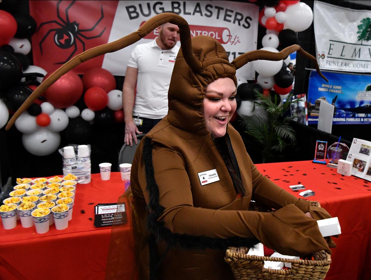 Amanda Taylor, wearing a cockroach costume, hands out car chargers while staffing the Bug Blasters Pest Control booth with Tanner Jones (at rear) and Aiyana Wurst during Wednesday's Business Expo at the Abilene Convention Center.