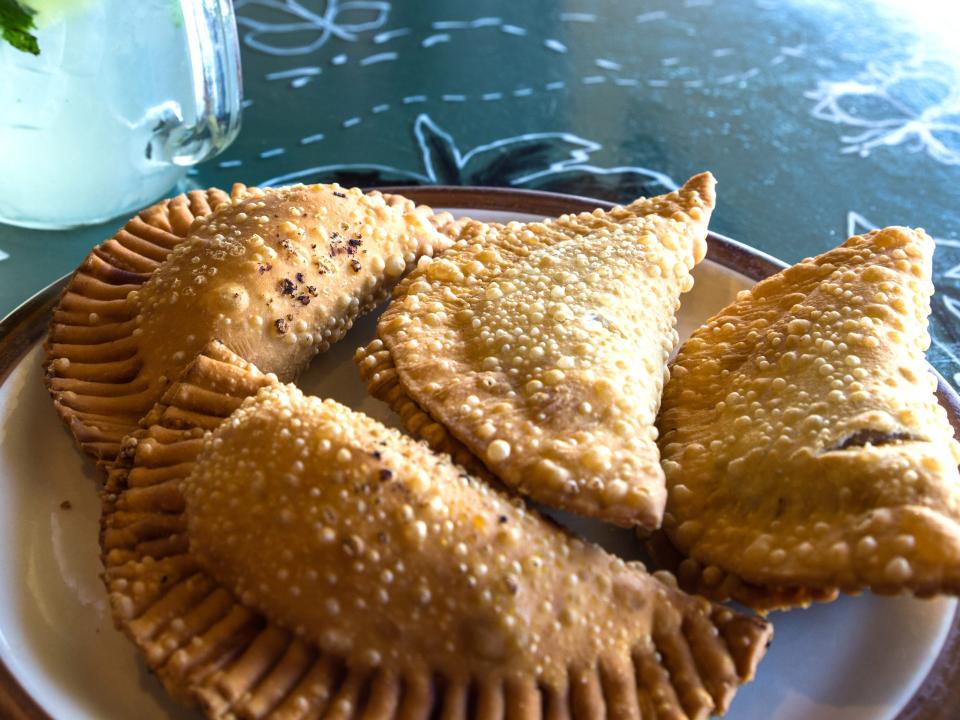 four empanadas on a white and brown plate