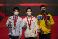 Zhang Boheng, center, of China, with his gold medal, Daiki Hashimoto, left, of Japan, with his silver medal, and Ilia Kovtun, of Ukraine, pose for photos and video during the podium ceremony after their men's all-around finals in the FIG Artistic Gymnastics World Championships in Kitakyushu, western Japan, Friday, Oct. 22, 2021. (AP Photo/Hiro Komae)