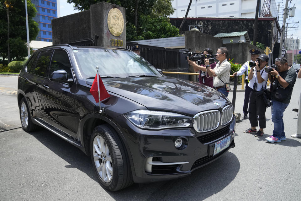 Periodistas toman fotos de un auto con matrícula diplomática y una bandera china que sale del Departamento de Asuntos Exteriores de Filipinas en Manila, Filipinas, el lunes 7 de agosto de 2023. (AP Foto/Aaron Favila)