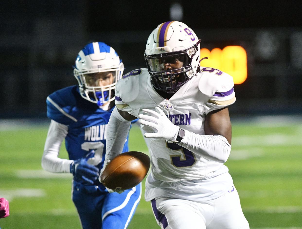 Western Beaver’s Dorrian McGhee carries the ball ahead of an Ellwood defender during Friday night’s game at Ellwood.