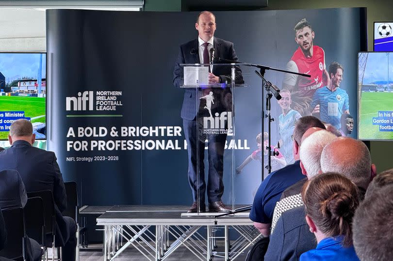 Photo shows Communities Minister Gordon Lyons speaking at Windsor Park