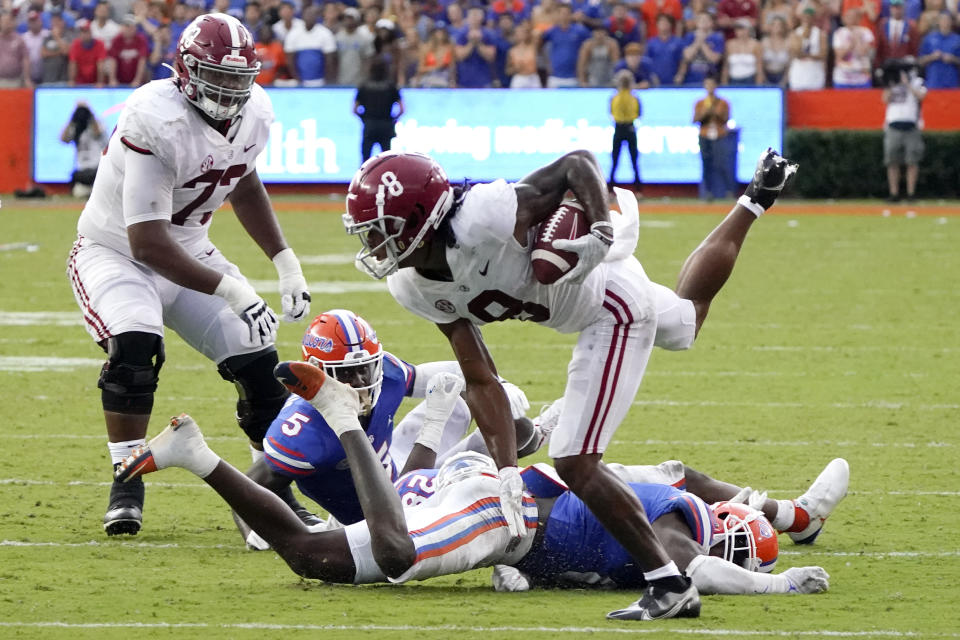 Alabama wide receiver John Metchie III (8) hurdles past Florida defensive players cornerback Kaiir Elam (5), linebacker Ty'Ron Hopper and safety Trey Dean III during the second half of an NCAA college football game, Saturday, Sept. 18, 2021, in Gainesville, Fla. (AP Photo/John Raoux)