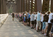 <p>Mourners join hands as thousands of people hold hands to remember last week’s shooting victims by joining hands on the Bill Thorpe Walking Bridge in downtown Fredericton on Monday, Aug. 13, 2018. (Photo from The Canadian Press/Stephen MacGillivray) </p>