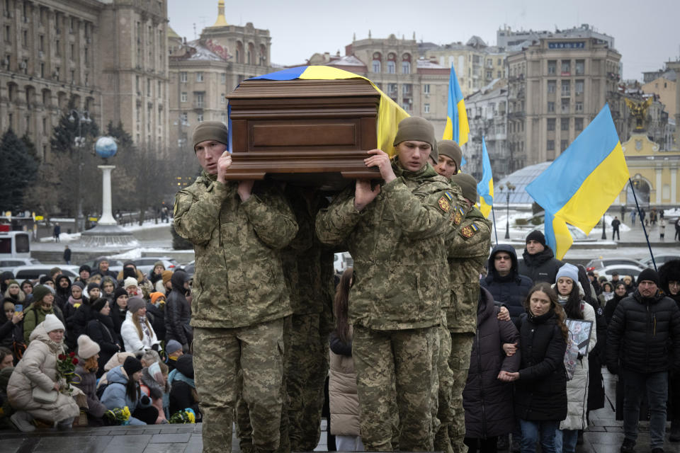 People kneel as soldiers carry the coffin of Ukrainian serviceman and famous Ukrainian poet Maksym Kryvtsov, who was killed in a battle with the Russian troops, during the funeral ceremony in St. Michael Cathedral in Kyiv, Ukraine, Thursday, Jan. 11, 2024. (AP Photo/Efrem Lukatsky)