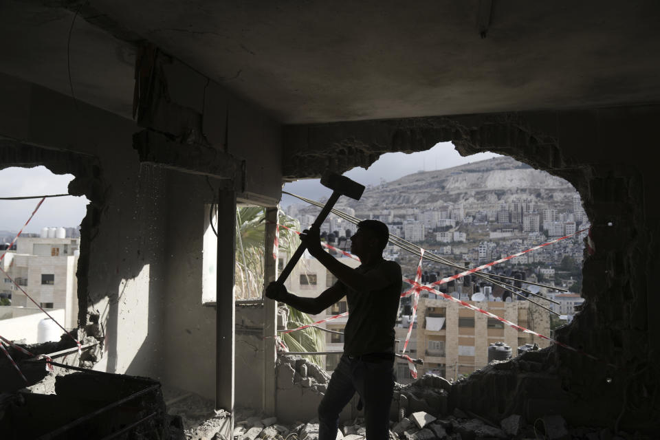 A Palestinian clears rubble after Israeli forces demolished the home of Osama Tawil, who was arrested in February for killing an Israeli soldier last year, in Nablus, Thursday, June 15, 2023. During the demolition operation, the Israeli military said troops operating in Nablus came under fire and fired back. A Palestinian man was killed, health officials said. (AP Photo/Nasser Nasser)