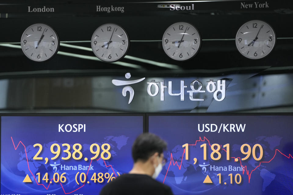 A currency trader walks by the screens showing the Korea Composite Stock Price Index (KOSPI), left, and the foreign exchange rate between U.S. dollar and South Korean won at a foreign exchange dealing room in Seoul, South Korea, Friday, Nov. 12, 2021. Shares were mostly higher in Asia on Friday after Wall Street benchmarks managed to close mostly higher. (AP Photo/Lee Jin-man)