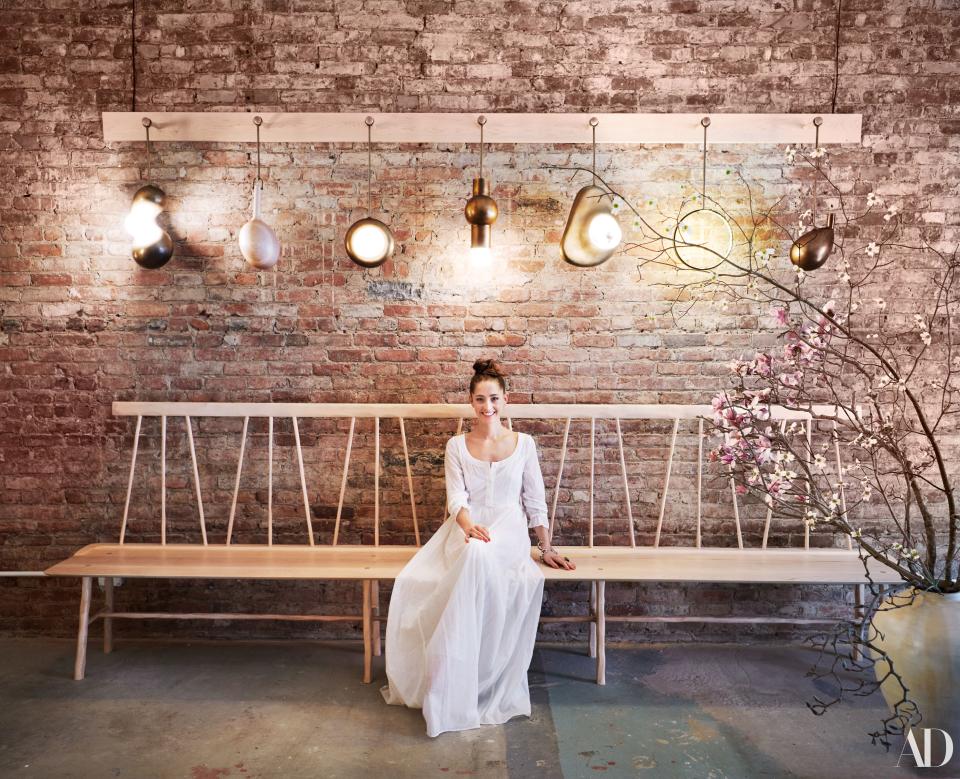 At her new Chinatown space in Manhattan, designer Anna Karlin perches on a hand-carved bench beneath sculptural glyph light fixtures.