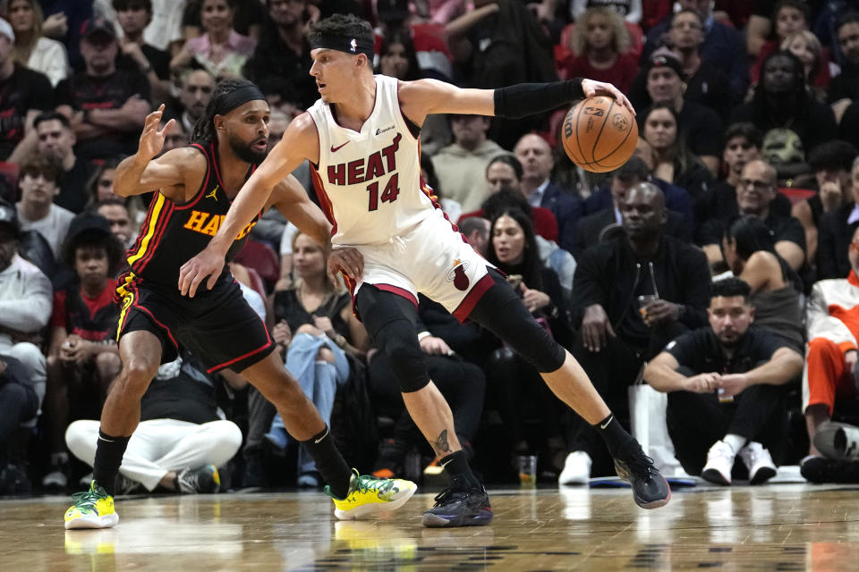 Miami Heat guard Tyler Herro (14) drives to the basket as Atlanta Hawks guard Patty Mills, left, defends during the first half of an NBA basketball game Friday, Dec. 22, 2023, in Miami. (AP Photo/Lynne Sladky)