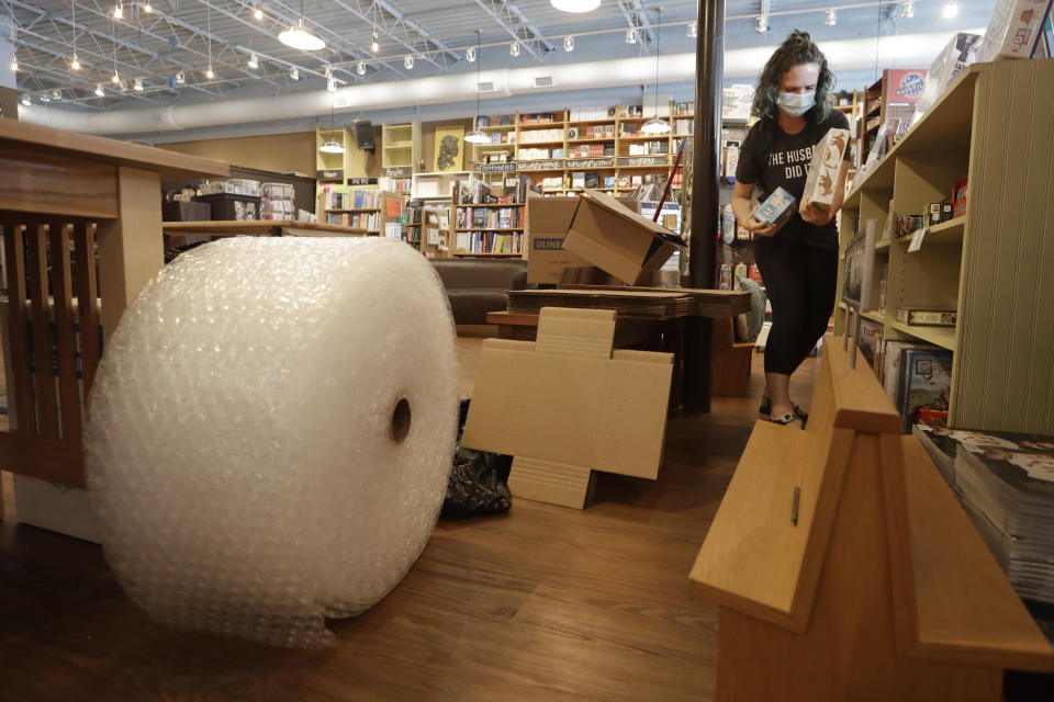 En esta fotografía del 25 de junio de 2020 materiales para envíos en la librería Parnassus Books junto a la empleada Cat Bock en Nashville, Tennessee. El piso de ventas de la librería se ha convertido en un centro de distribución por la pandemia. (Foto AP/Mark Humphrey)