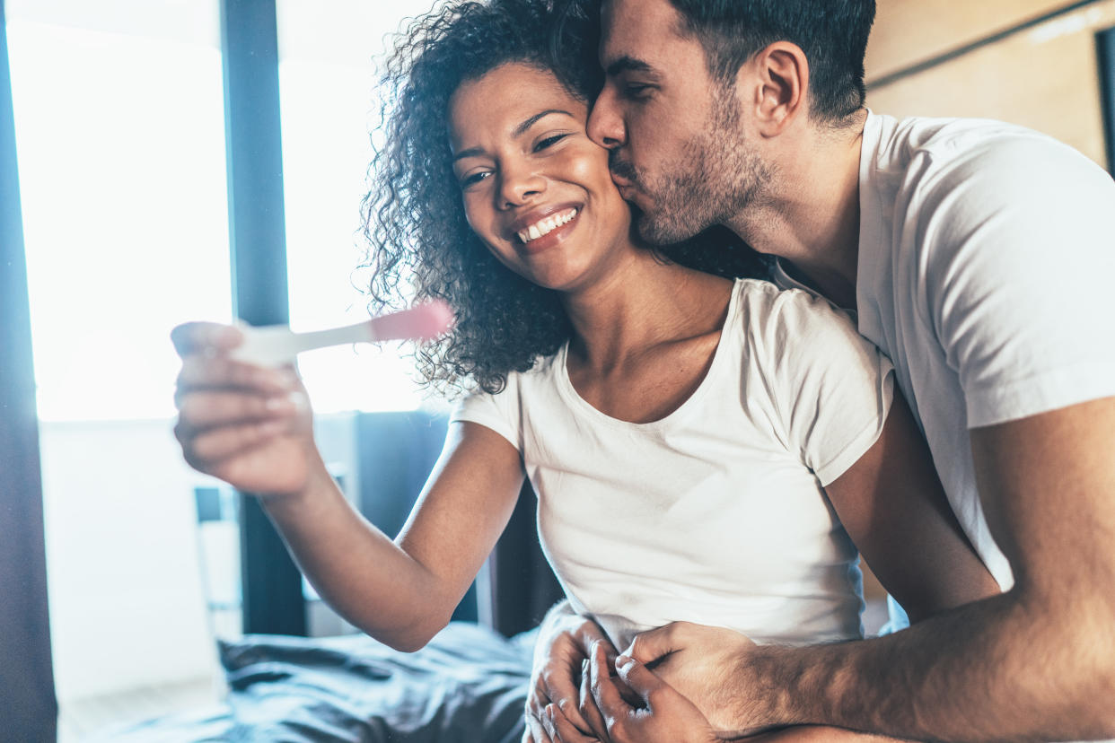 Couple happily looking at a positive pregnancy test. (Getty Images)