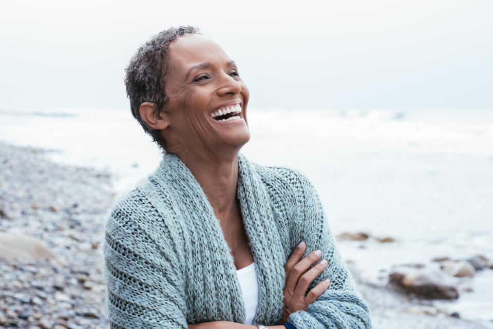 Woman smiling on beach and folding arms