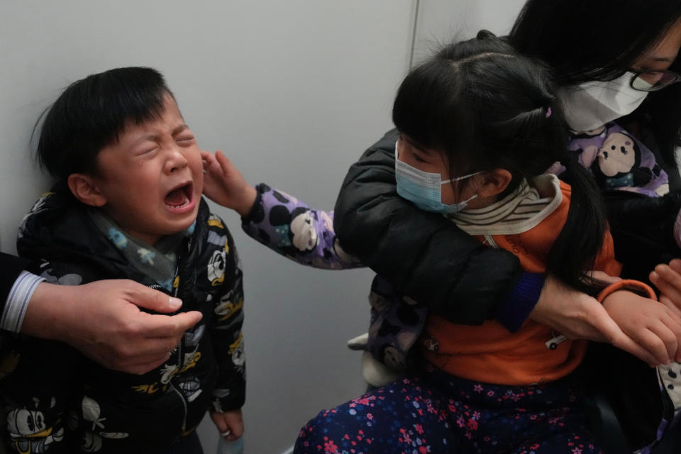FILE - A boy cries after receiving a dose of China's Sinovac COVID-19 coronavirus vaccine at a community vaccination center in Hong Kong on Feb. 25, 2022. The fast-spreading omicron variant is overwhelming Hong Kong, prompting mass testing, quarantines, supermarket panic-buying and a shortage of hospital beds. Even the morgues are overflowing, forcing authorities to store bodies in refrigerated shipping containers. (AP Photo/Kin Cheung, File)