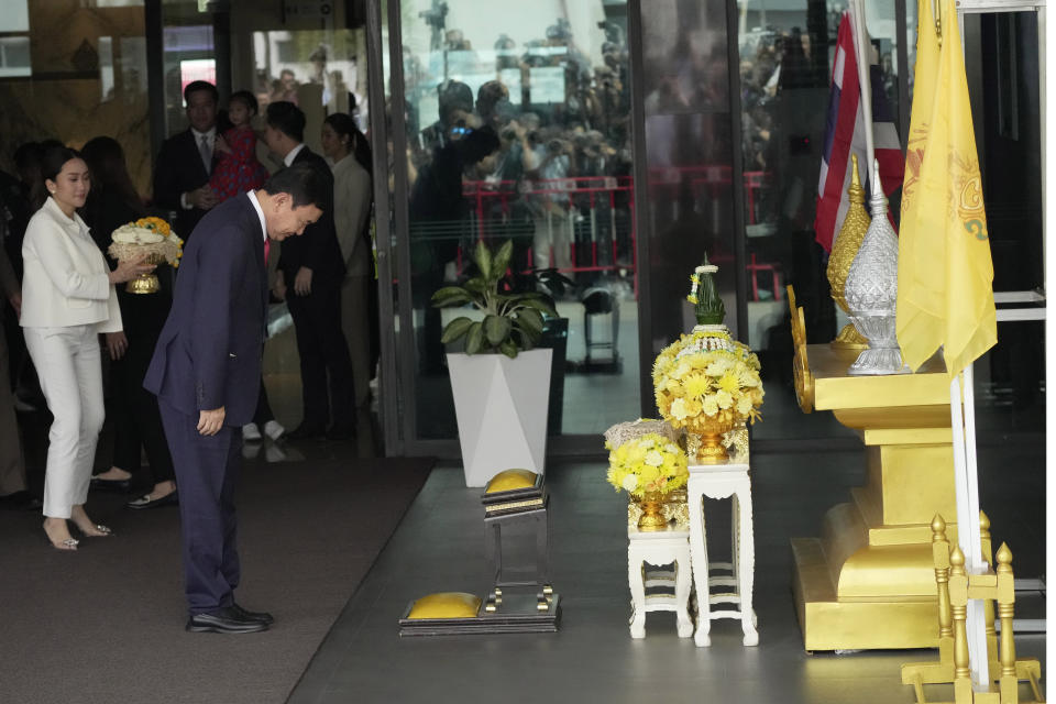 Thailand's former Prime Minister Thaksin Shinawatra, second left, prays in front of a portrait of King Maha Vajiralongkorn as he arrives at Don Muang airport in Bangkok, Thailand, Tuesday, Aug. 22, 2023. (AP Photo/Sakchai Lalit)