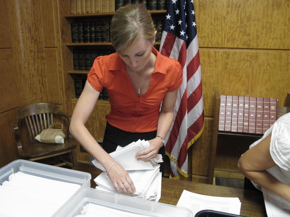 Beth Herzog, a public information officer for North Dakota Secretary of State Al Jaeger, counts initiative petitions in Jaeger's office in the North Dakota Capitol on Monday, Aug. 6, 2012. The initiative, which was submitted Monday, would set aside part of North Dakota's oil tax collections for wildlife, wetlands and conservation projects. (AP Photo/Dale Wetzel)