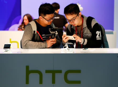 FILE PHOTO: Attendees view the new HTC U Ultra at the HTC stand at the Mobile World Congress in Barcelona, Spain March 1, 2017. REUTERS/Paul Hanna/File Photo