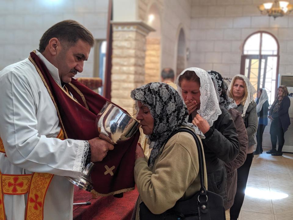 A woman takes communion at a church in Tal Tamr (Richard Hall/The Independent)Richard Hall / The Independent