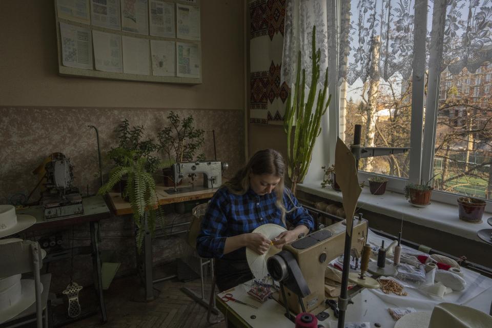 Ukrainian hat maker for high-end designer brand Ruslan Baginskiy 'RB', Svetlana Podgainova, works inside a college classroom turned into a working space for the company in Lviv, western Ukraine, Friday, March 25, 2022, after fleeing Kyiv. Searching for safety but determined not to leave Ukraine, the brand is among the businesses that are uprooting amid war. Podgainova worried about her family back in the separatist-held territory of Luhansk in eastern Ukraine, where pro-Moscow separatists have been fighting for control for nearly eight years. (AP Photo/Nariman El-Mofty)