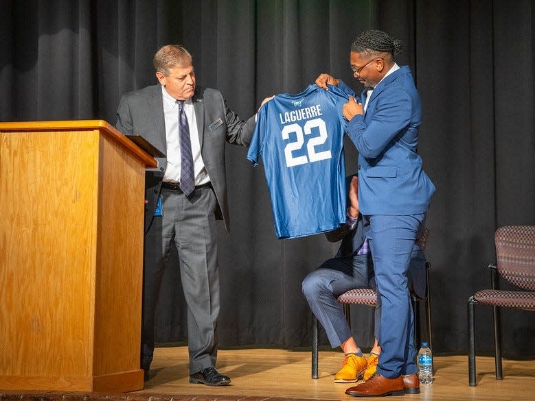 Florida State College at Jacksonville President John Avendano (left) presents a school jersey to Quan Laguerre, the brother of AJ Laguerre, one of the victims of last year's Dollar General shooting. FSCJ, The Players Championship and the PGA Tour have partnered to endow a scholarship in AJ. Laguerre's name to the school.