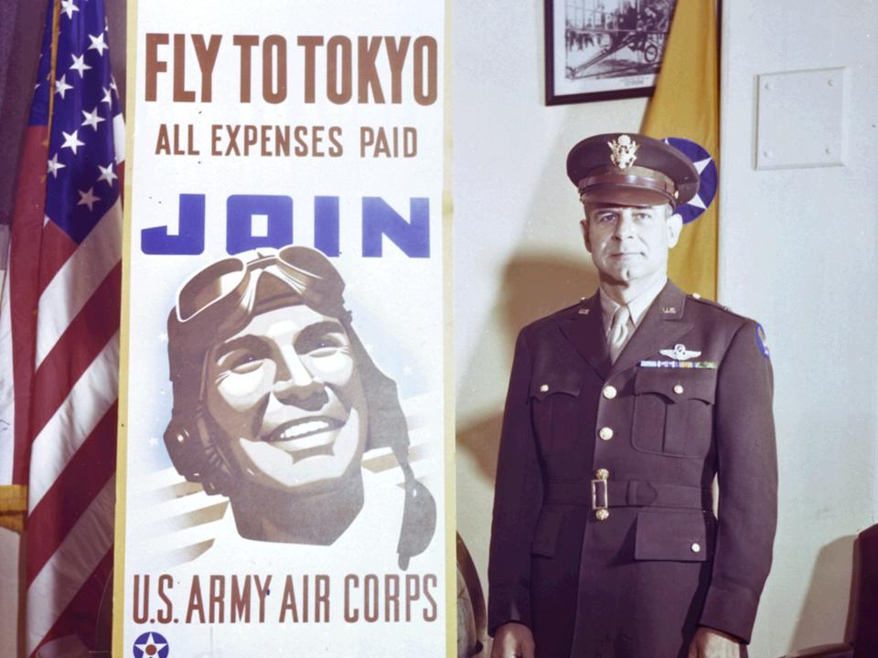 Portrait of American military Brigadier General James Doolittle (1896 - 1993) as he stands next to an Army Air Corps recruiting poster, 1943