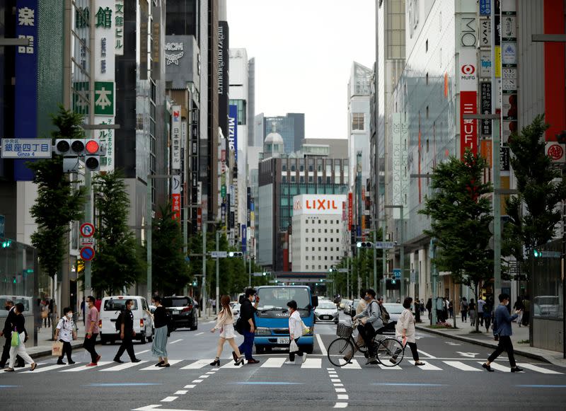 Passersby wearing protective face masks, following the outbreak of the coronavirus disease (COVID-19), walk on the crossing in Tokyo