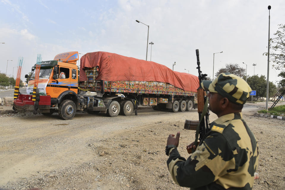 An Indian Border Security Force soldier guards as a truck carrying wheat from India moves to pass through the Attari-Wagah border between India and Pakistan, near Amritsar, India, Tuesday, Feb. 22, 2022. India's foreign ministry says it has sent off tons of wheat to Afghanistan to help relieve desperate food shortages, after New Delhi struck a deal with neighboring rival Pakistan to allow the shipments across the shared border. (AP Photo/Prabhjot Gill)