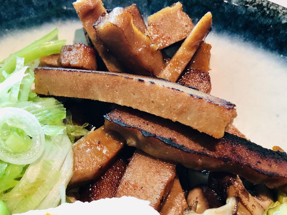 close up of a bowl with sticky rice topped with bbq glazed seitan, caramelised king oyster mushrooms, asparagus, edamame, spring onions, carrots and a vegan egg made with miso infused coconut and sriracha mayo