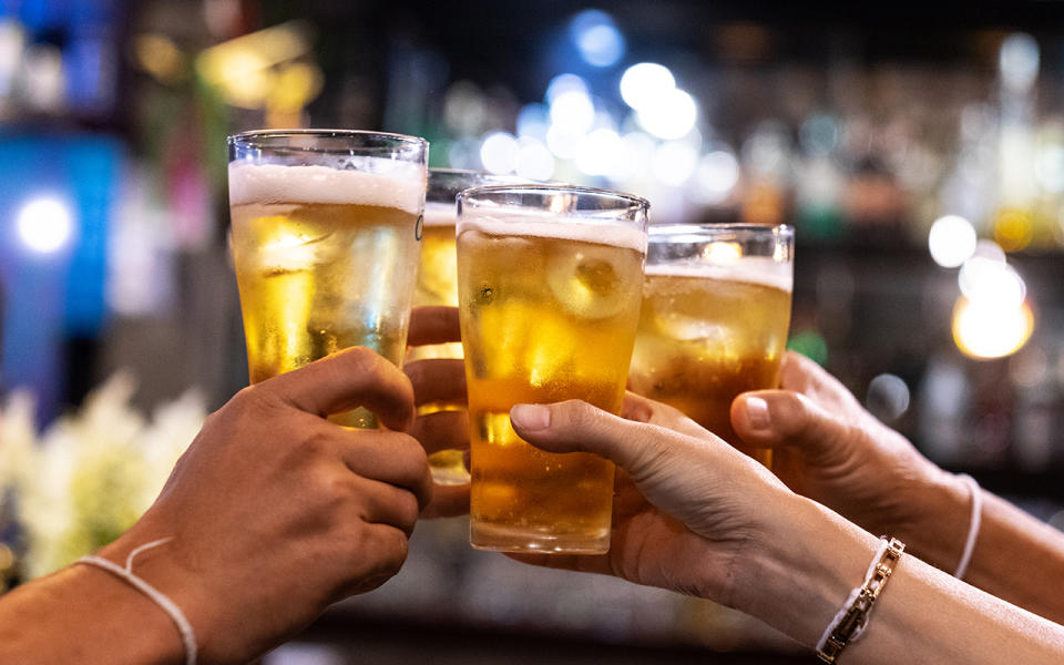 Group of happy friends drinking and toasting beer at a bar. Source: Getty 