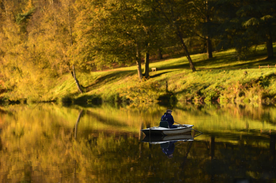 Autumn trees reflected in a lake with fishing boat