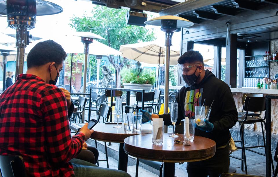 A busboy clears a table in the outdoor seating area of The Abbey Food & Bar on January 29, 2021 in West Hollywood, California. - California has lifted the statewide "stay at home" ban, paving the way for the return of activities such as outdoor dining with a reopening permit, in line with new strict regulations aimed at preventing the spread of Covid-19. (Photo by VALERIE MACON / AFP) (Photo by VALERIE MACON/AFP via Getty Images)