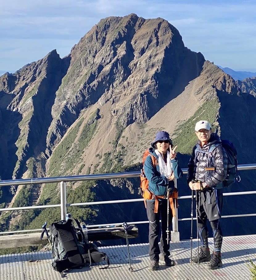 賈淑麗去年6月與先生第N次攀登玉山，夫妻站立處為玉山北峰，後面的山頭為玉山主峰。圖片來源 / 賈淑麗提供