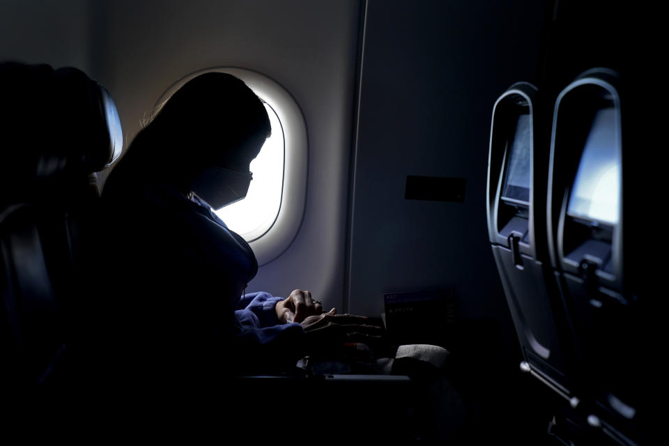 FILE - In this Wednesday, Feb. 3, 2021, file photo, a passenger wears a face mask she travels on a flight from Hartsfield-Jackson International Airport in Atlanta. In a lawsuit filed Tuesday, March 29, 2022, Florida and 20 other states are suing to halt the federal government's pandemic requirement that people wear masks on planes, trains and other public transport. (AP Photo/Charlie Riedel, File)