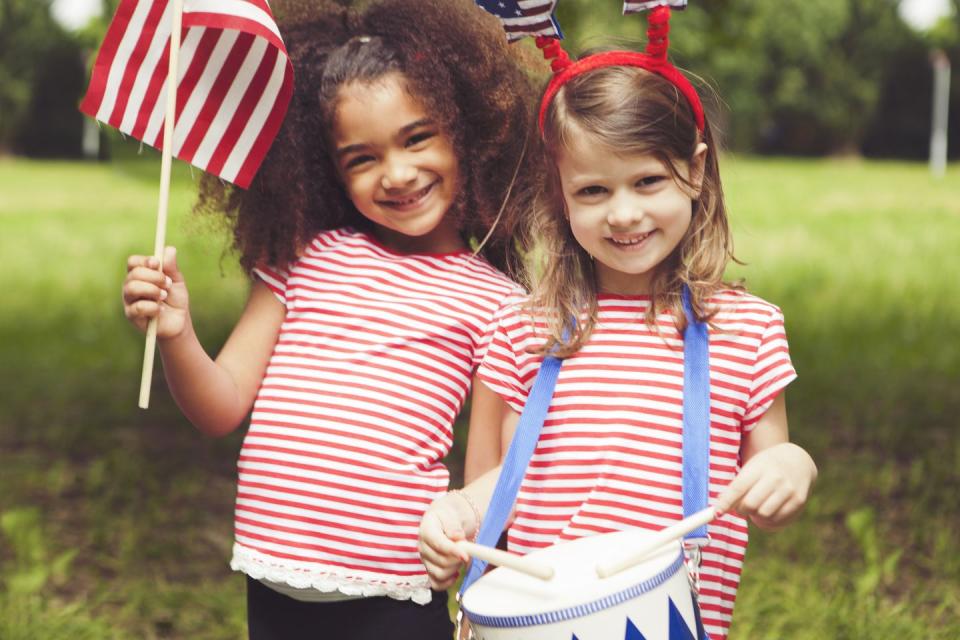 4th of july activities two smiling girls one holding a drum set and the other an american flag