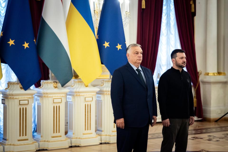 Hungarian PM Viktor Orban stands with Ukrainian president Volodymyr Zelensky in front of the European Union, Hungarian and Ukrainian flags (AP)