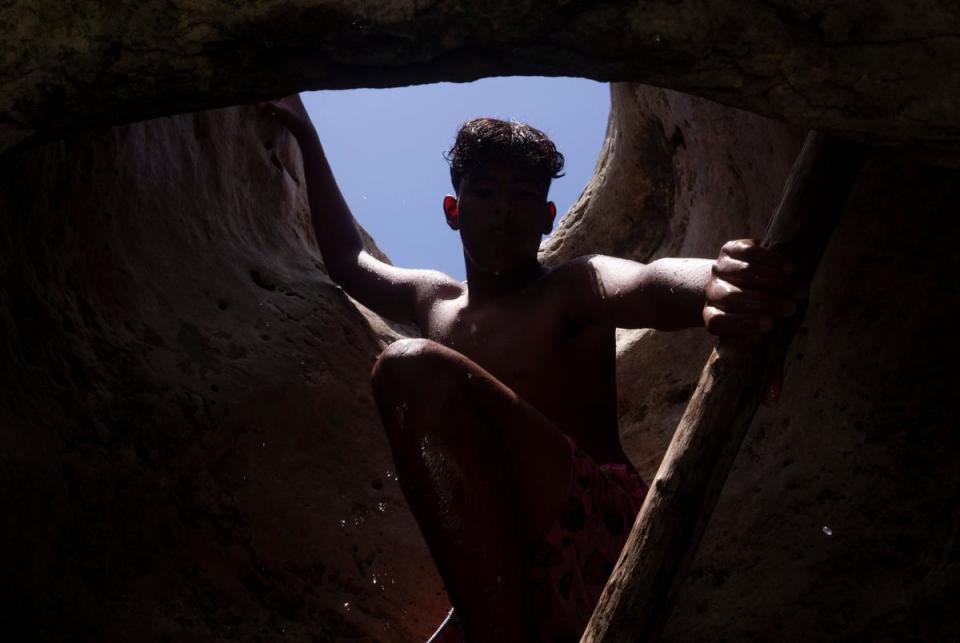 Pablo Zapato, 14, of Mission, climbs out of the water and up through a hole in the limestone at Upper McKinney Falls at McKinney Falls State Park in Austin on July 29, 2023.