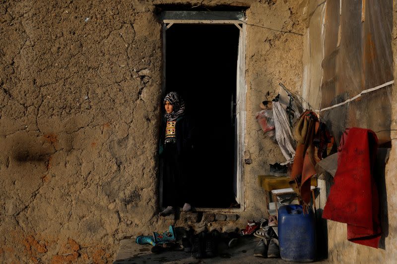 Sister of Amrullah, a child who died due to cold, stands at her home in Kabul