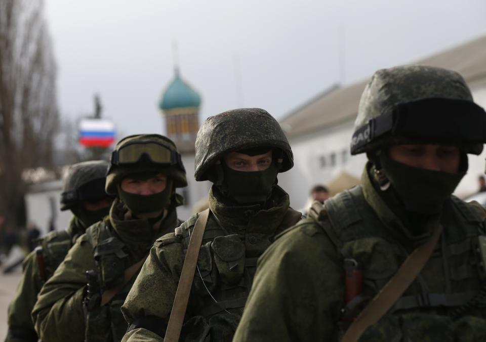 Military personnel, believed to be Russian servicemen, march outside the territory of a Ukrainian military unit in the village of Perevalnoye outside Simferopol