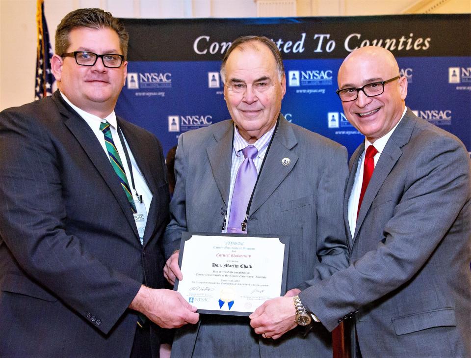 Chemung County legislator Marty Chalk, center, accepts a certificate from New York State Association of Counties President Charles H. Nesbitt Jr., left, and NYSAC Executive Director Stephen J. Acquario.