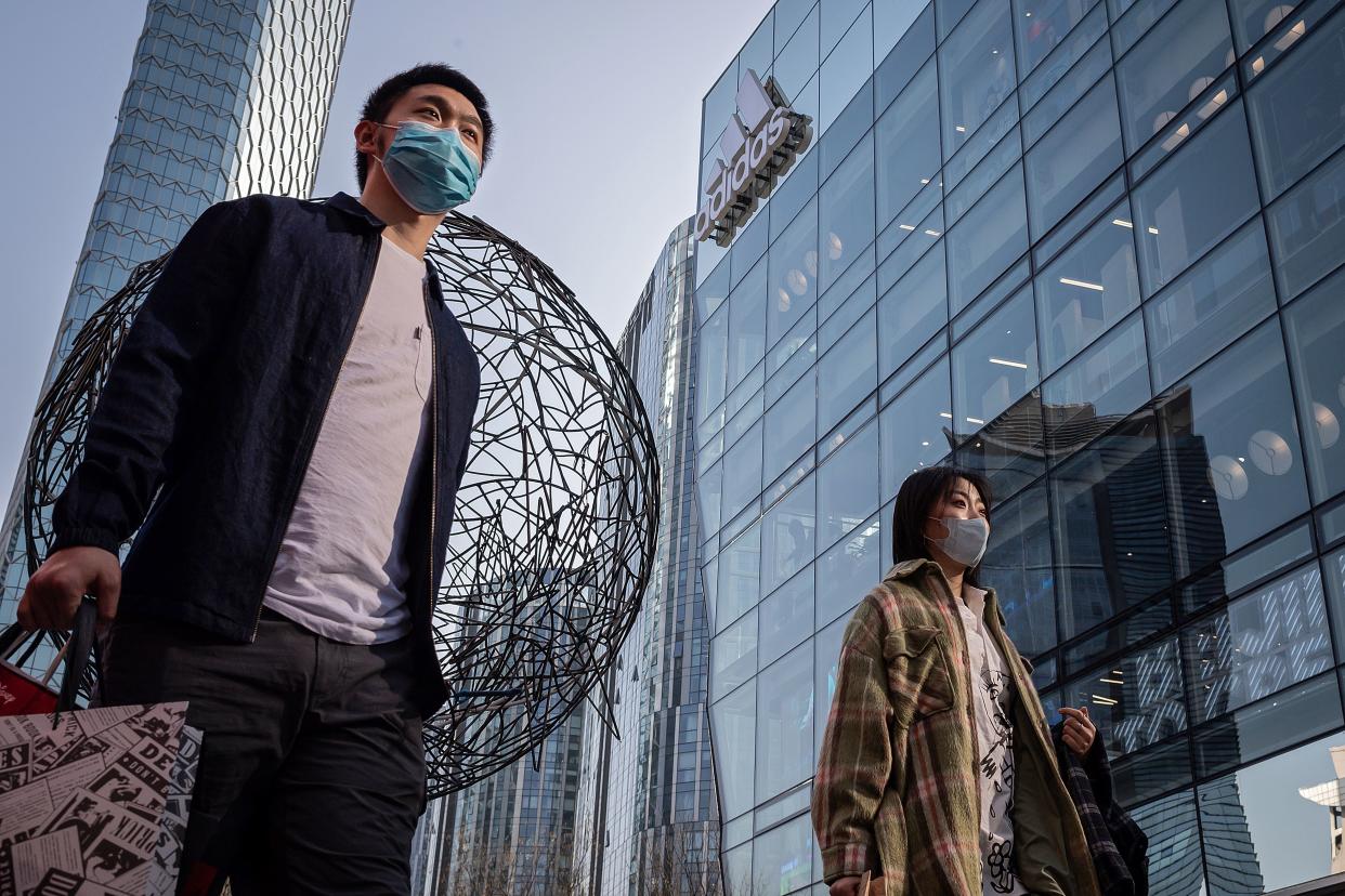 A woman and a man wearing facemasks as a preventive mesure against the COVID-19 coronavirus walk outside a shopping mall in Beijing on March 11, 2020. - Mainland China, where all people arriving in Beijing from abroad will be placed in quarantine for two weeks, has 80,778 cases, with 3,158 deaths and 61,475 people cured. (Photo by NICOLAS ASFOURI / AFP) (Photo by NICOLAS ASFOURI/AFP via Getty Images)