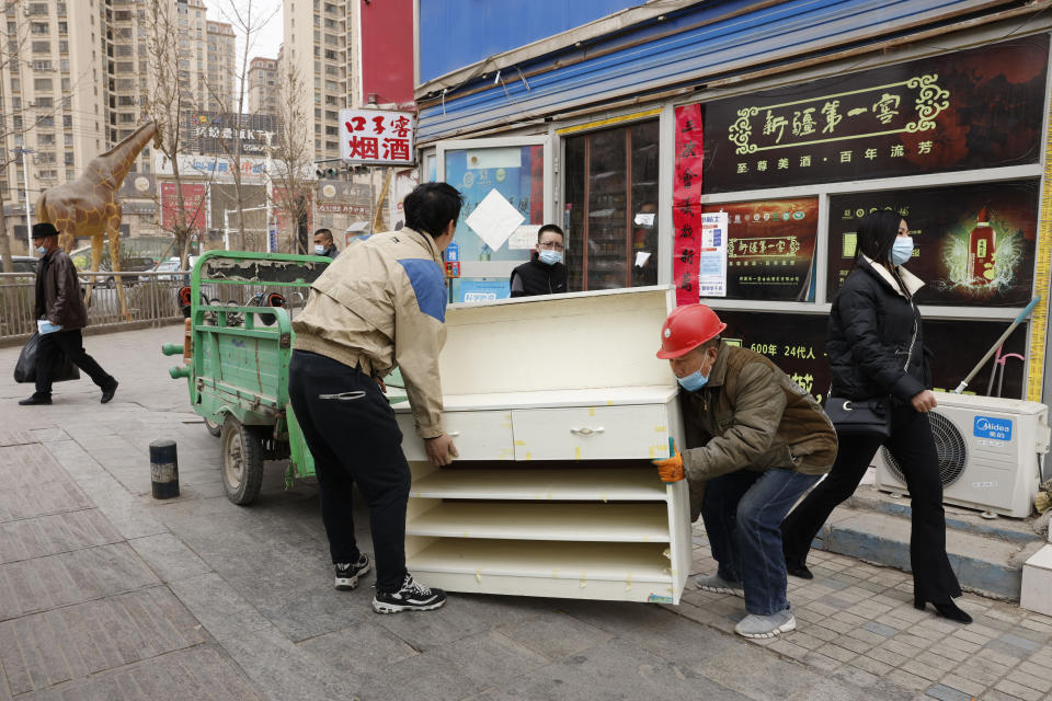 Workers move a used cabinet in Aksu in western China's Xinjiang Uyghur Autonomous Region on March 18, 2021. China is going global with its campaign to deflect criticism over its policies in the northwestern region of Xinjiang. The region's government on Wednesday, June 2, organized a transcontinental zoom call showcasing economic development and poverty elimination. (AP Photo/Ng Han Guan)