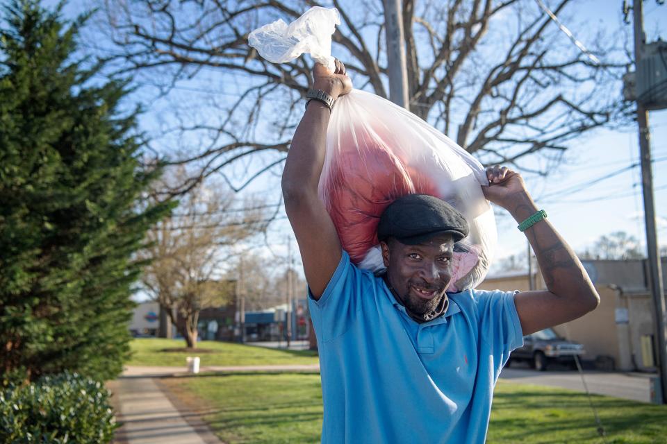 Jeffery Glenn carries a bag of clothes from Trinity Methodist Church in West Asheville, March 31, 2022.