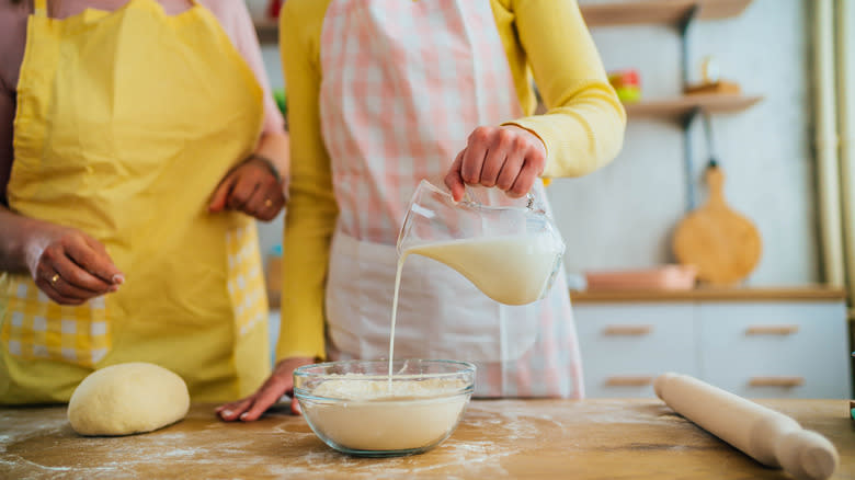 Bakers pouring milk onto dough