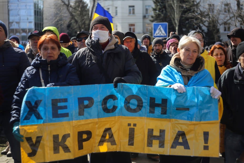 People hold a Ukrainian flag with a sign that reads: ‘Kherson is Ukraine’ during a rally against the Russian occupation in the southern city in March  (AP)