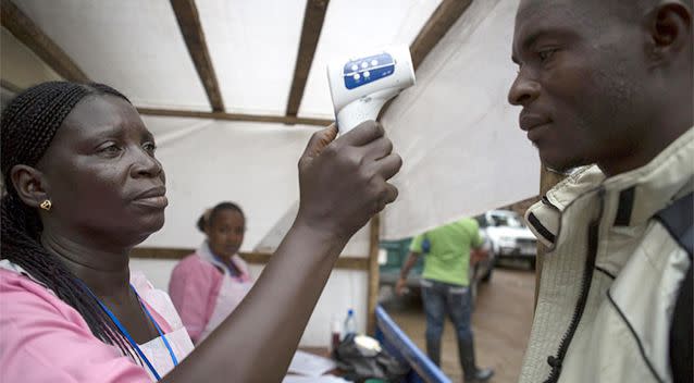 A woman takes the temperature of a social mobilizer before he handles health supplies in Freetown, Sierra Leone. Photo: REUTERS/Bindra/UNICEF