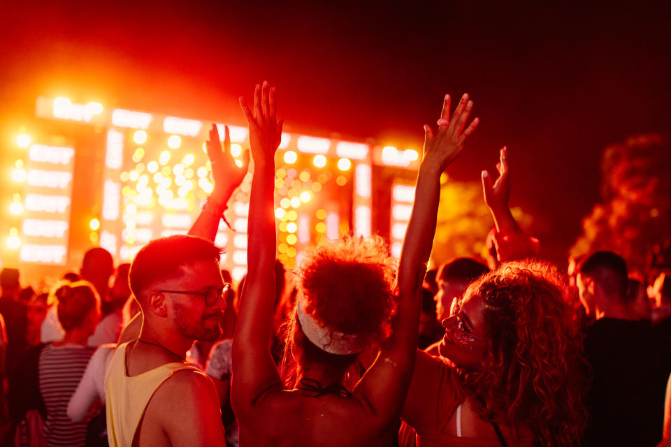 A young crowd is enthusiastic at a night performance during a festival, with people smiling and putting their hands in the air. (Photo via Getty Images)