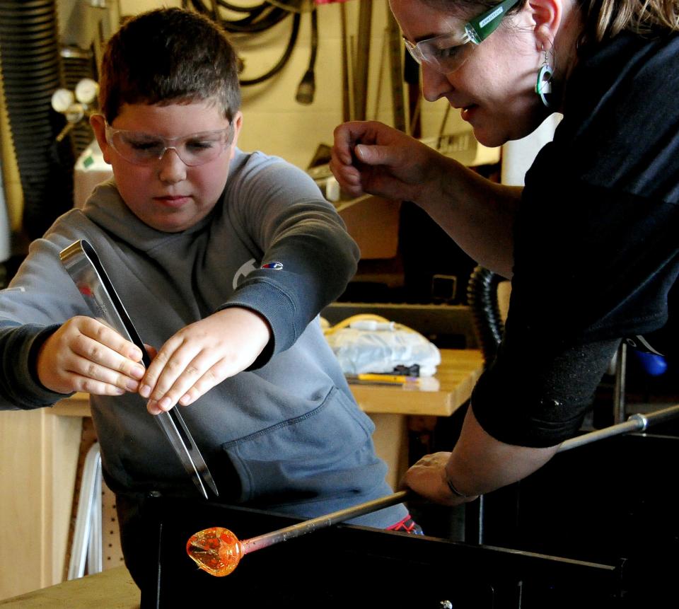 Under the watchful eye of Smithville art teacher Jennifer Winkler, Clayton Saurer works to form petals on his hot piece of glass