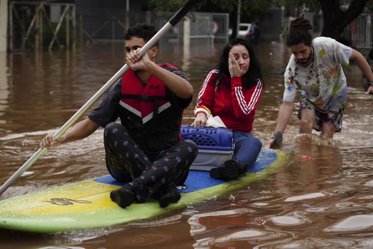 People evacuate on a surfboard from a neighborhood flooded by heavy rains, in Canoas, Rio Grande do Sul state, Brazil, May 4, 2024. / Credit: Carlos Macedo/AP